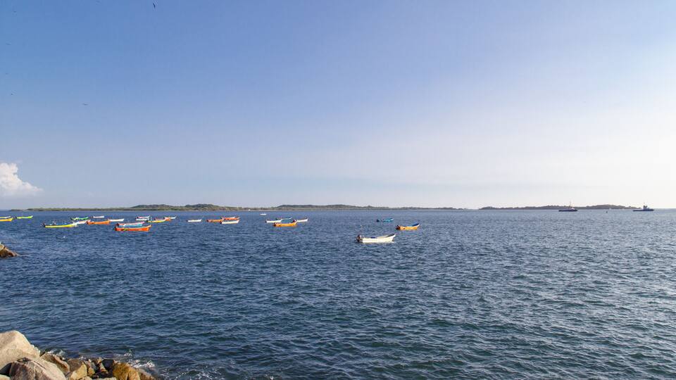 A calm sea with several small boats and a distant island.