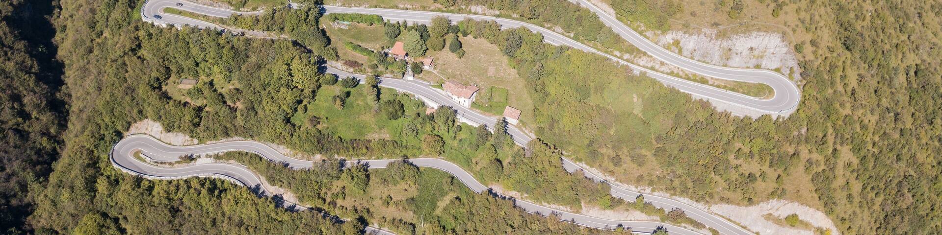 Up and down drone aerial view of the mountain road in Italy that connects the village of Nebro to Selvino. Amazing aerial view of the mountain bends creating beautiful shapes