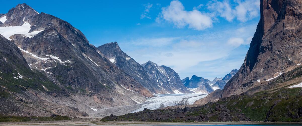 A glacier between mountains with a clear sky.