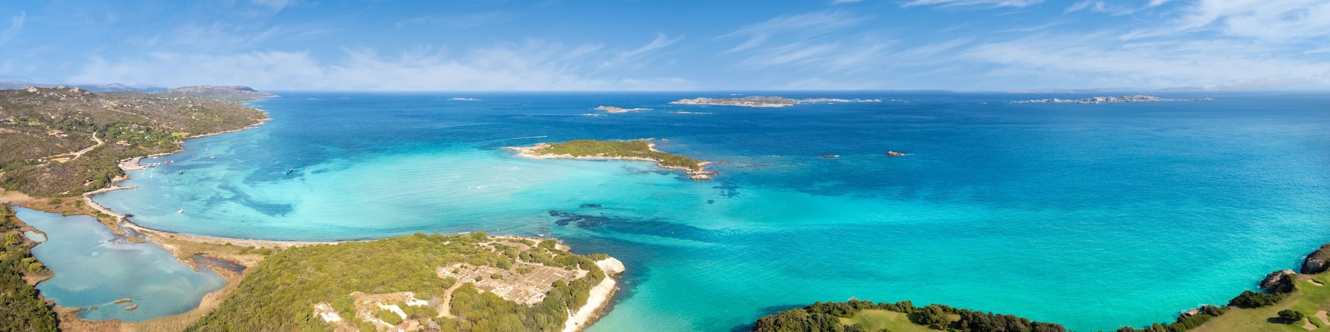 Un paisaje costero con aguas turquesas cristalinas, una playa arenosa y un campo de golf.