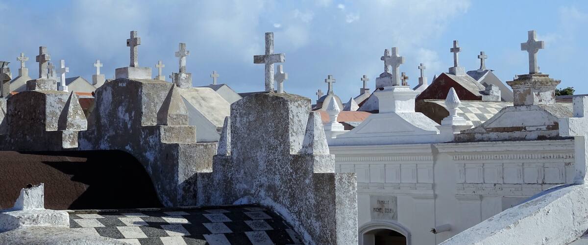 A cemetery with numerous tombstones and crosses under a clear blue sky.