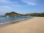 Une plage avec des empreintes de pas, un bateau et des maisons sur une colline.