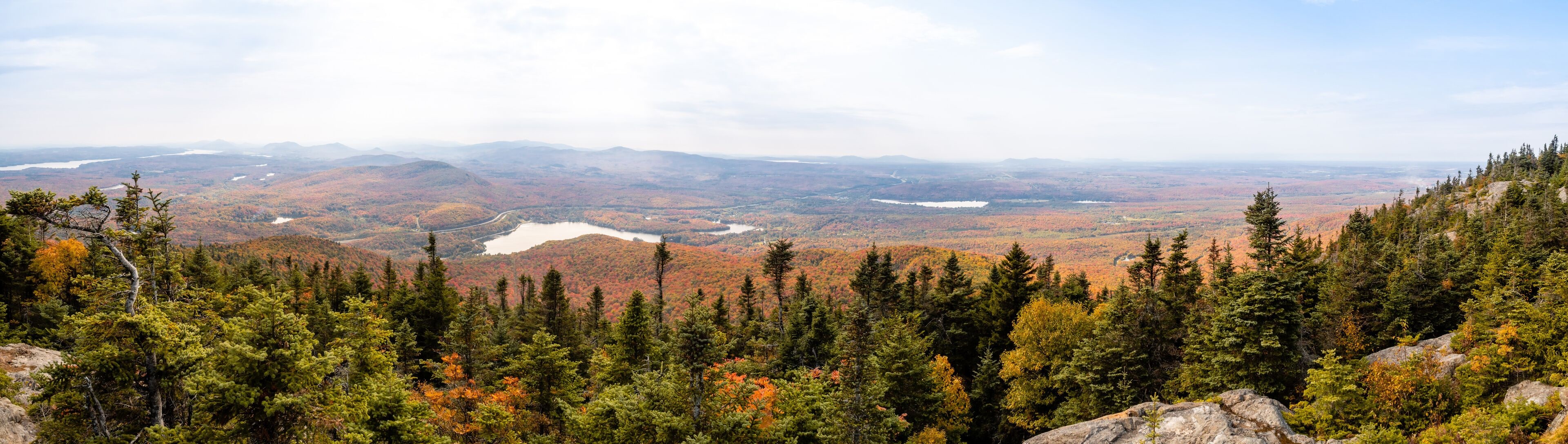 A mountainous landscape with dense forests and a lake in the valley.