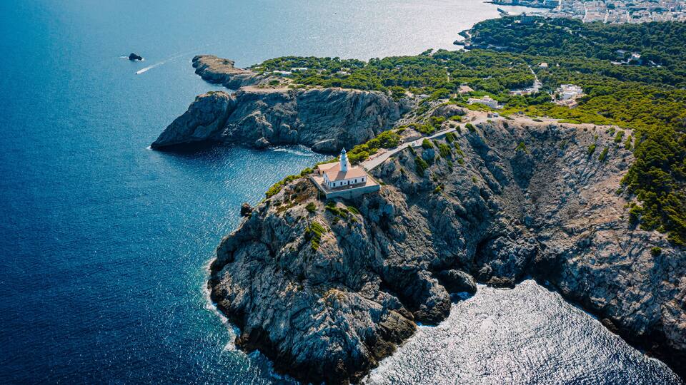 A coastal landscape with rocky cliffs, a lighthouse, and a small settlement.