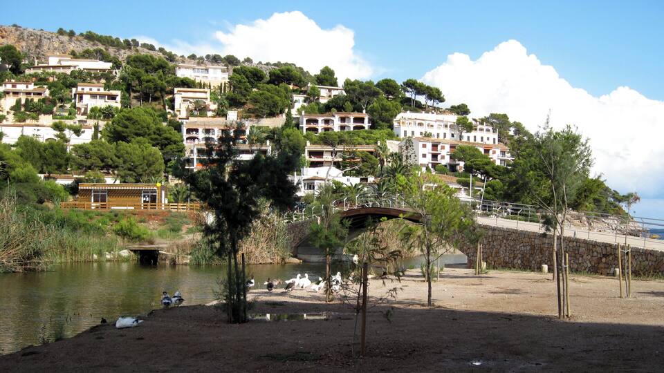 A coastal town with white buildings, a river, and a bridge.