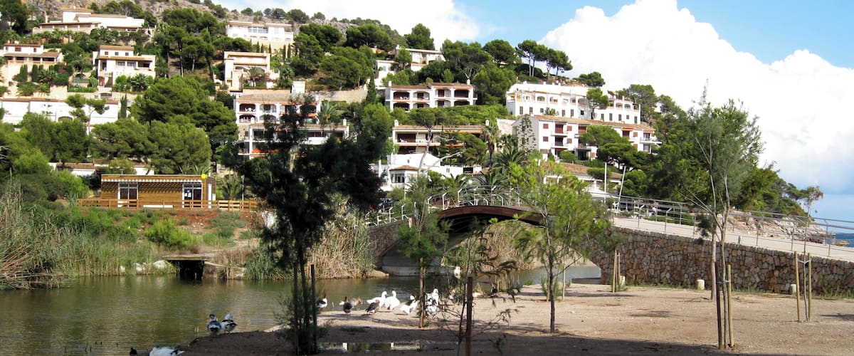 A coastal town with white buildings, a river, and a bridge.