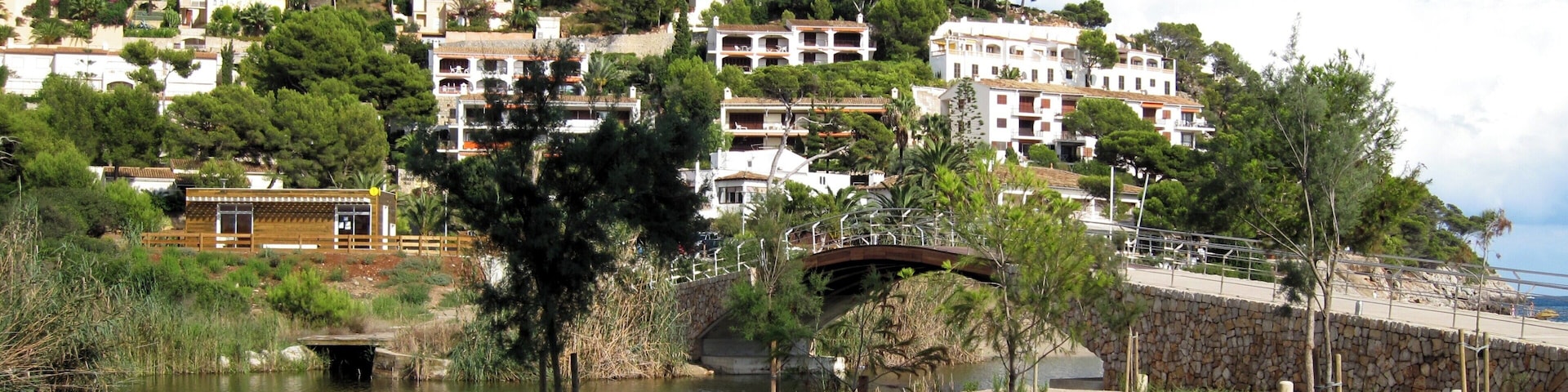 A coastal town with white buildings, a river, and a bridge.