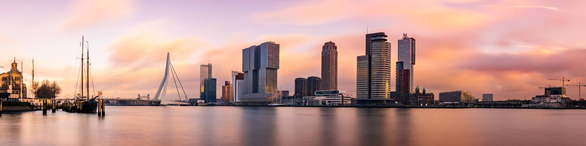 A city skyline with modern skyscrapers and a cable-stayed bridge over a calm body of water.