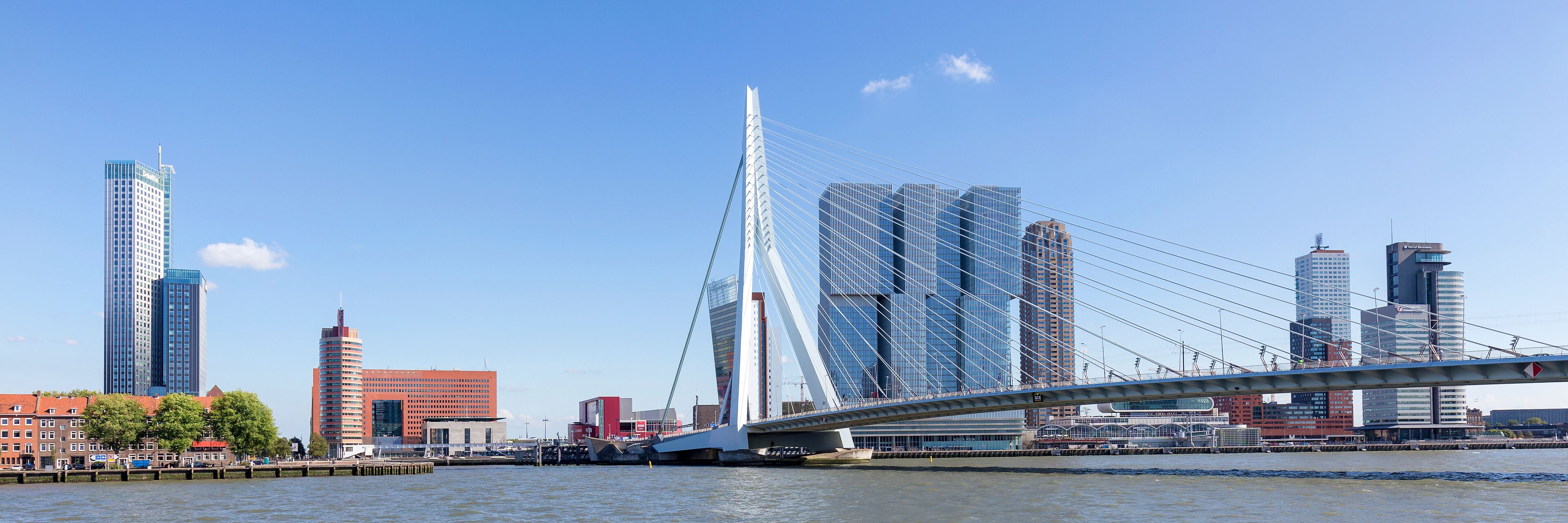 A modern bridge spanning a river with high-rise buildings in the background.