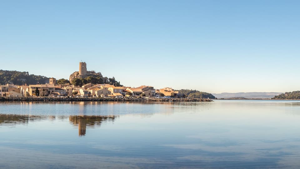 A calm lake with a historic town on an island, featuring a prominent tower and traditional buildings.