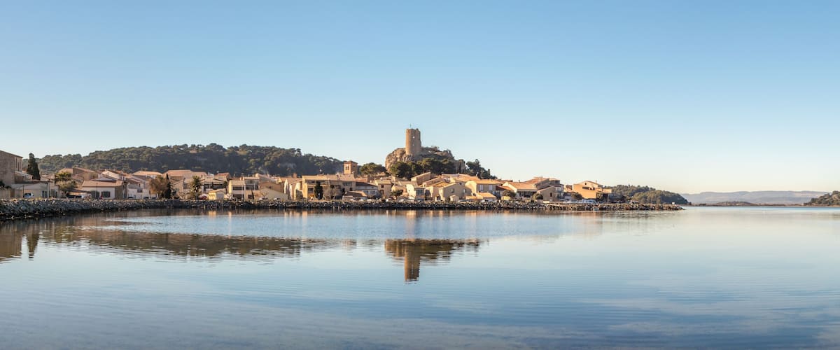 A calm lake with a historic town on an island, featuring a prominent tower and traditional buildings.