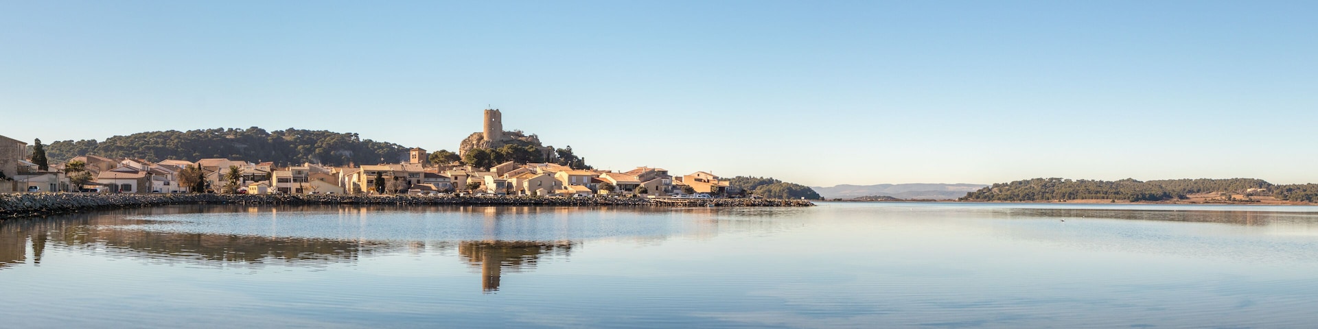 A calm lake with a historic town on an island, featuring a prominent tower and traditional buildings.