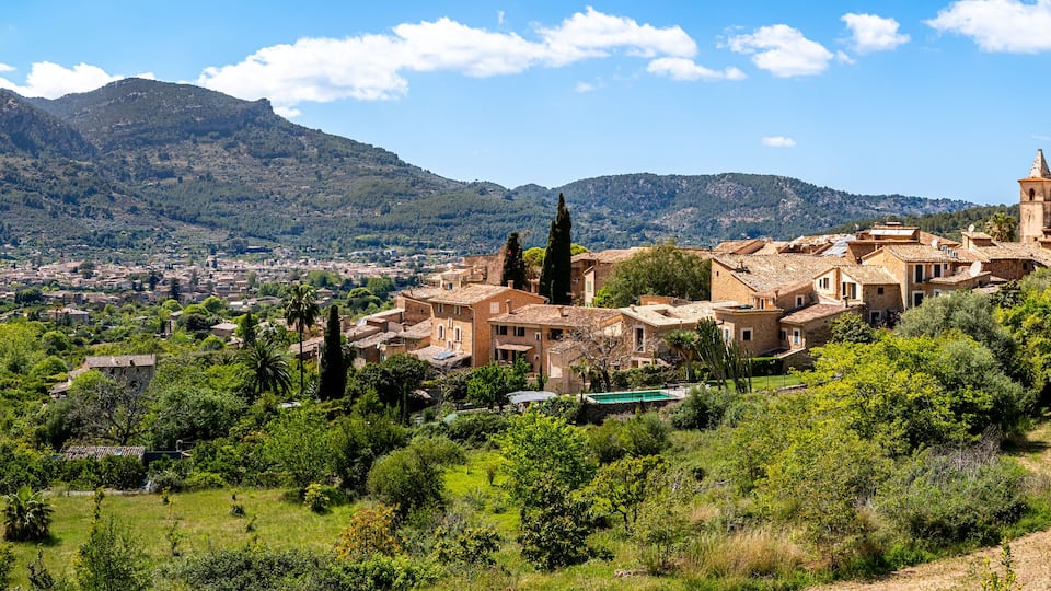 A mountainous landscape with a historic town featuring stone buildings and a prominent tower.