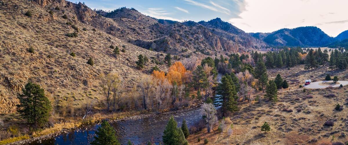 A river flowing through a mountainous landscape with autumn-colored trees and a clear sky.