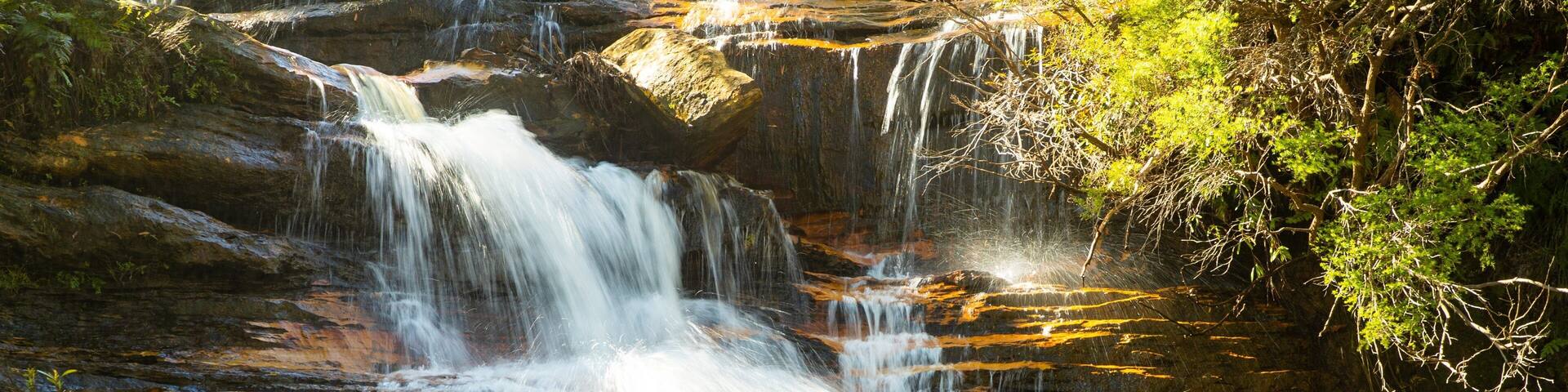 A multi-tiered waterfall surrounded by lush greenery.