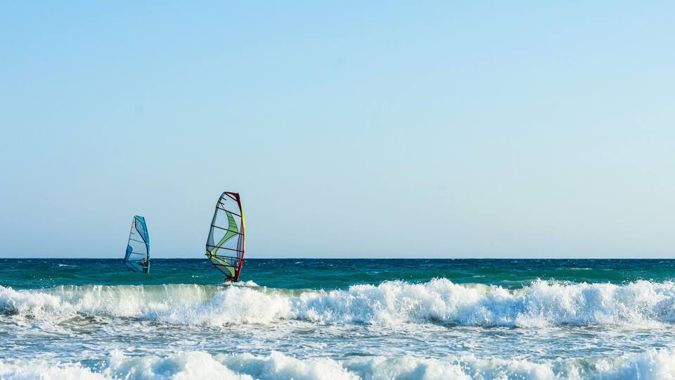 Windsurfers in the sea on Crete on sunset. Windsurfing in Heraklion