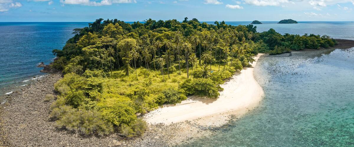 A tropical island with a sandy beach and dense green forest.