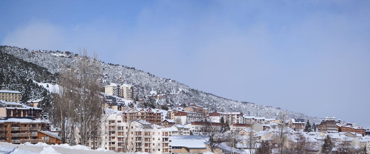 A snow-covered mountain town with buildings and a ski resort.