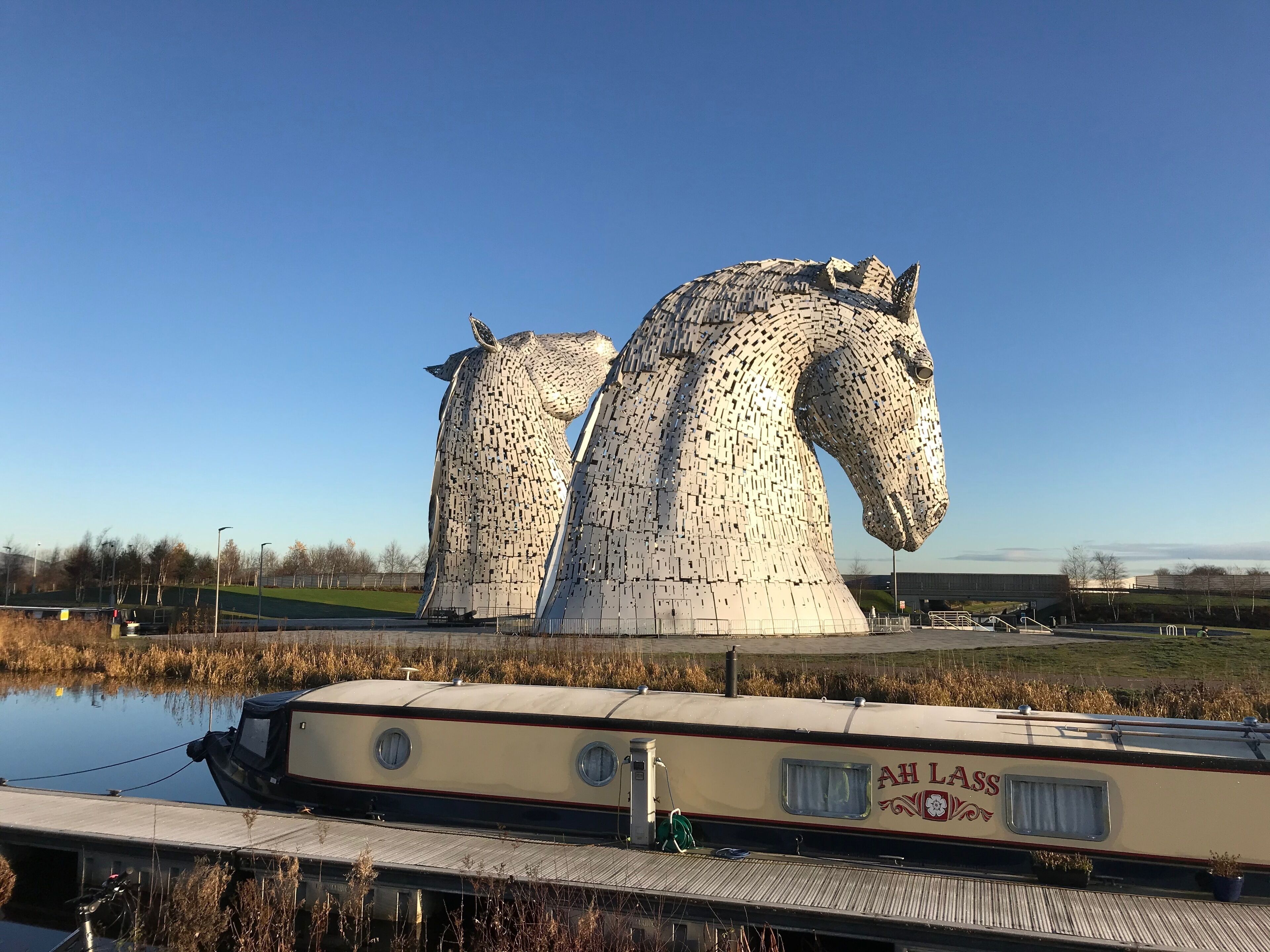 The Kelpies, a pair of large, white, metallic horse sculptures in a park.