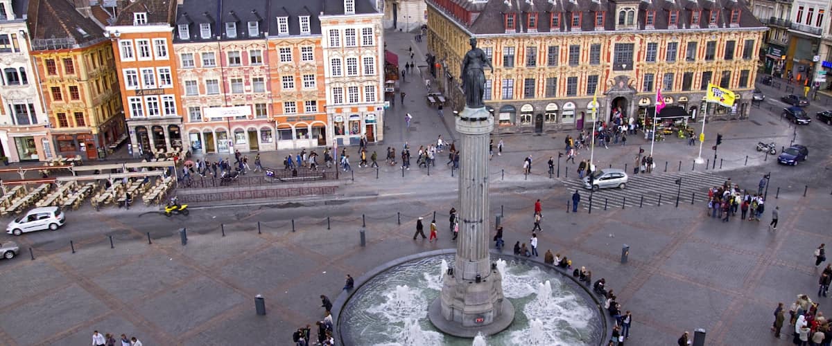 A historic square with a central fountain, surrounded by ornate buildings and a statue.
