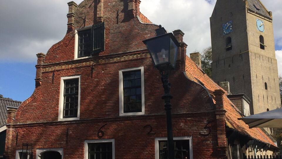 A historic brick building with a clock tower, a street lamp, and a sign for a chocolatier.