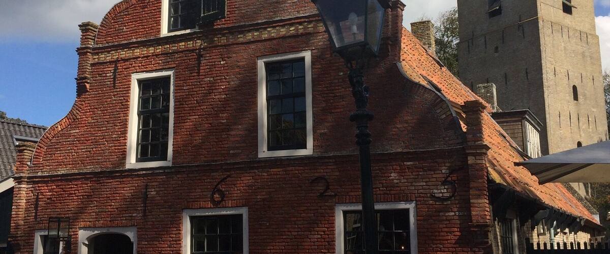 A historic brick building with a clock tower, a street lamp, and a sign for a chocolatier.