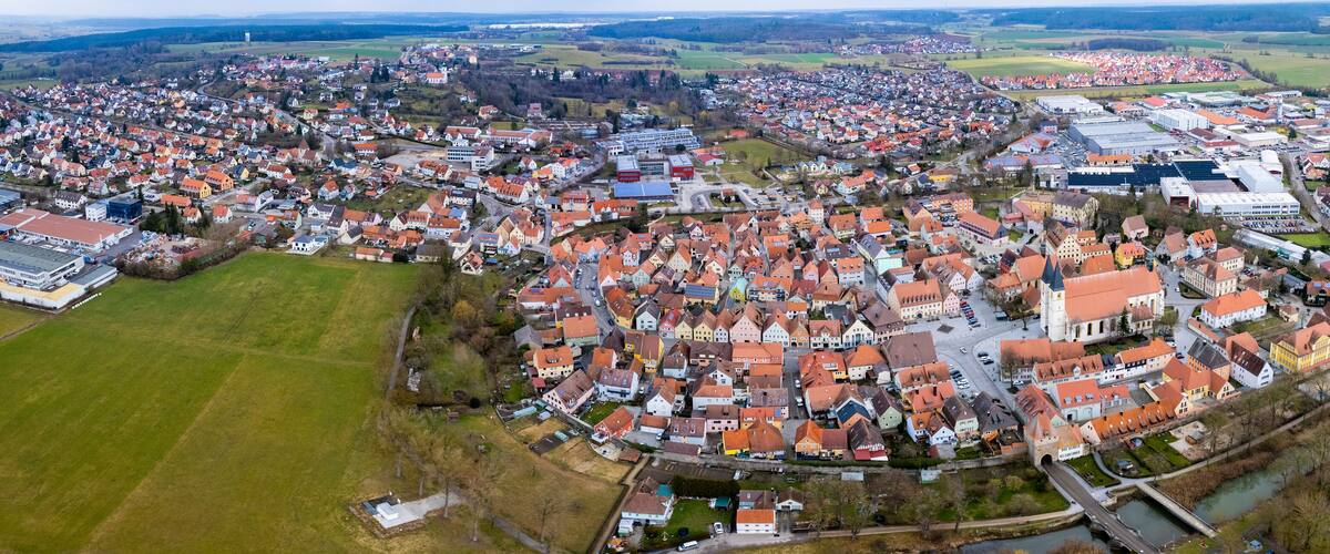 An aerial view of a town with a river, surrounded by fields and industrial buildings.