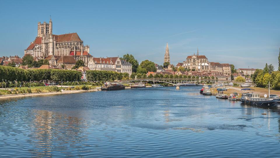A river with boats, a bridge, and historic buildings including a cathedral.