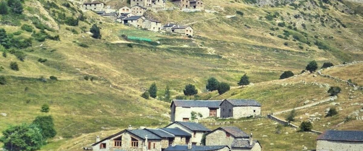 A rural village nestled in a valley with a prominent hill in the background.