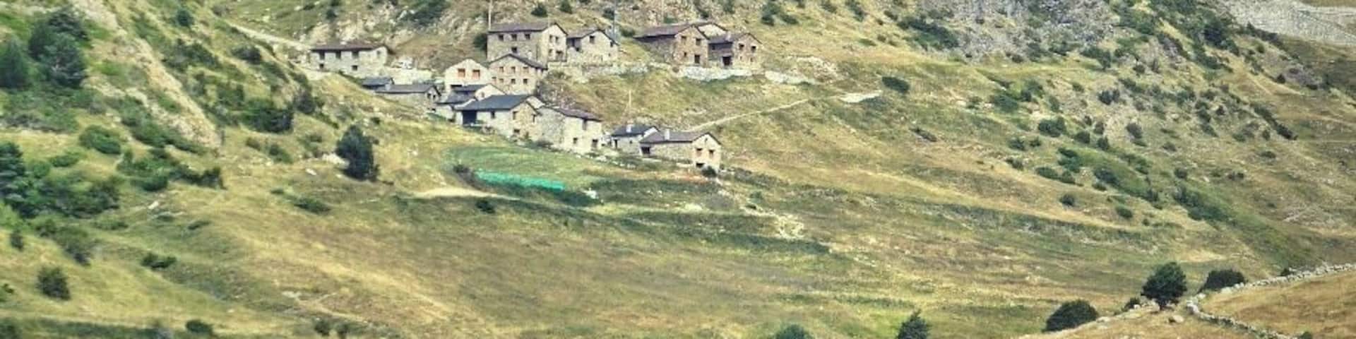 A rural village nestled in a valley with a prominent hill in the background.