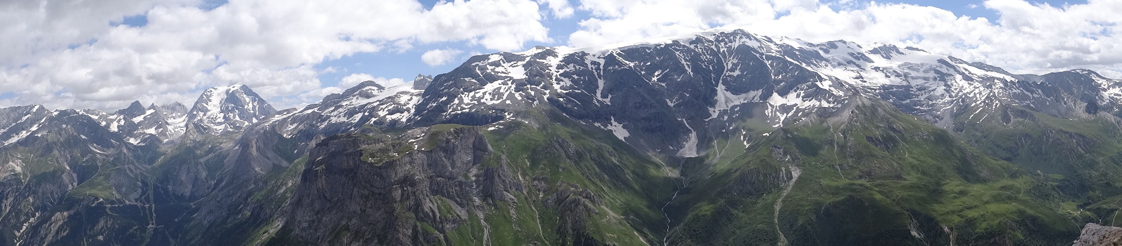 Ein Gebirge mit schneebedeckten Gipfeln und üppig grünen Tälern.