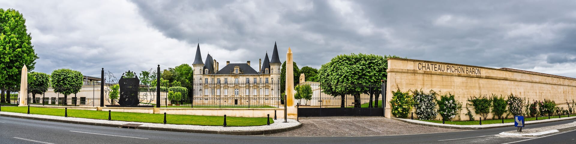 Chateau Pichon Baron, a historic building with a prominent tower and a large entrance gate.