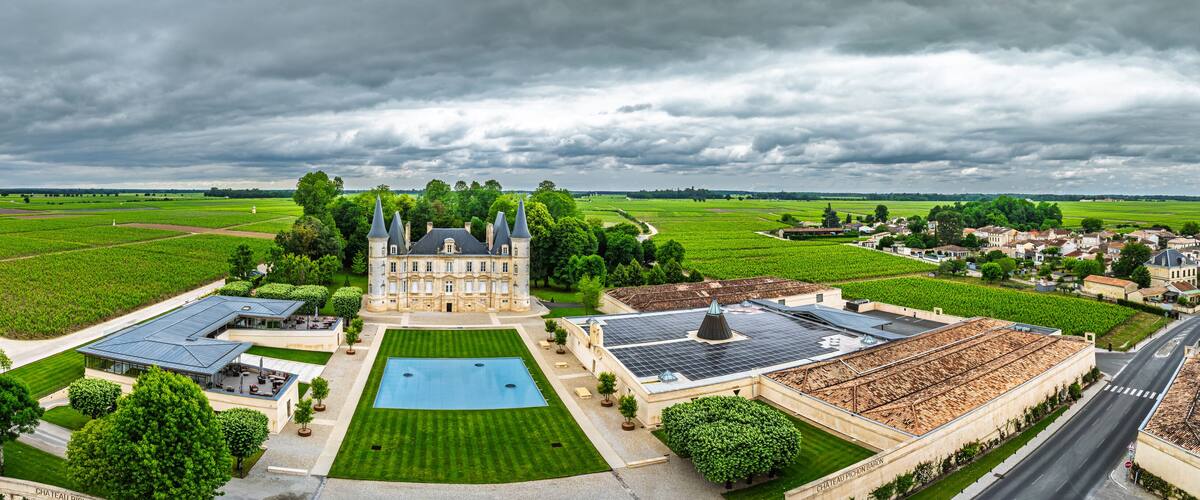 A large estate with a central building, expansive green fields, and a swimming pool.