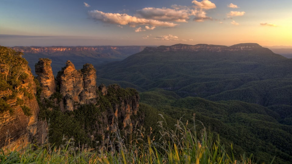 A mountainous landscape with prominent rock formations and dense forest.