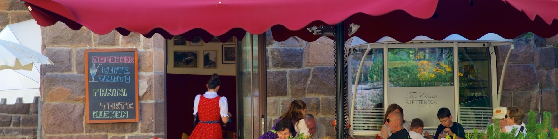Ein Restaurant mit Außenbereich, Steinmauern und einer roten Markise.