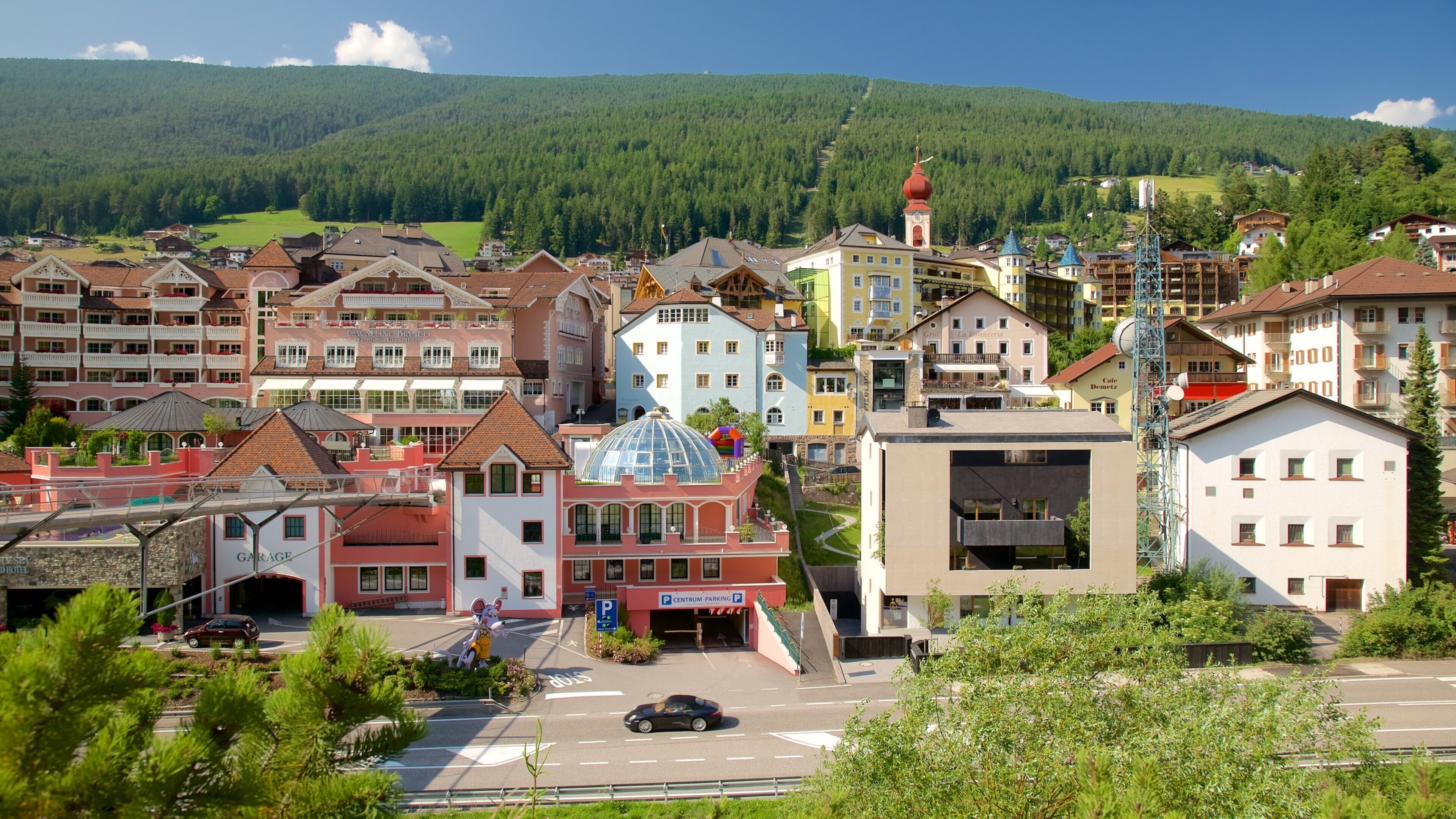 A town with colorful buildings, a prominent church with a red dome, and a parking area.