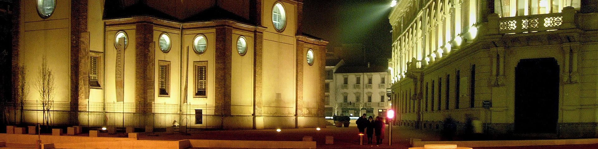 A historic building with a clock tower and a dome, illuminated at night.