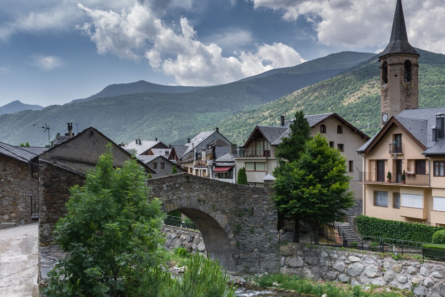 A dramatic sky above the mountains menaces the peace of a little village & its typical buildings, stone bridge & churg at Esterri d'Aneu, Spain; Shutterstock ID 1120561814; Purchase Order: -