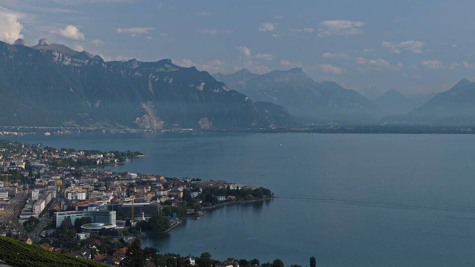 A panoramic view of a coastal city with mountains in the background.