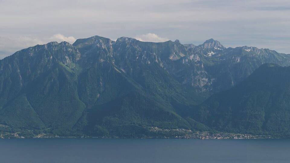 A mountain range with a lake in the foreground and a town at the base.