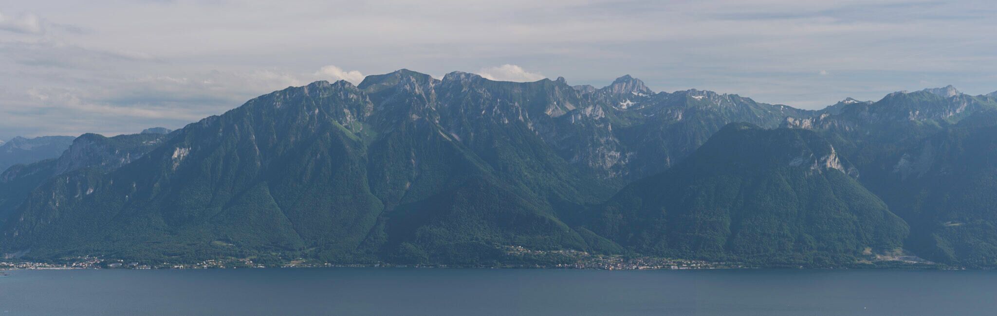 A mountain range with a lake in the foreground and a town at the base.