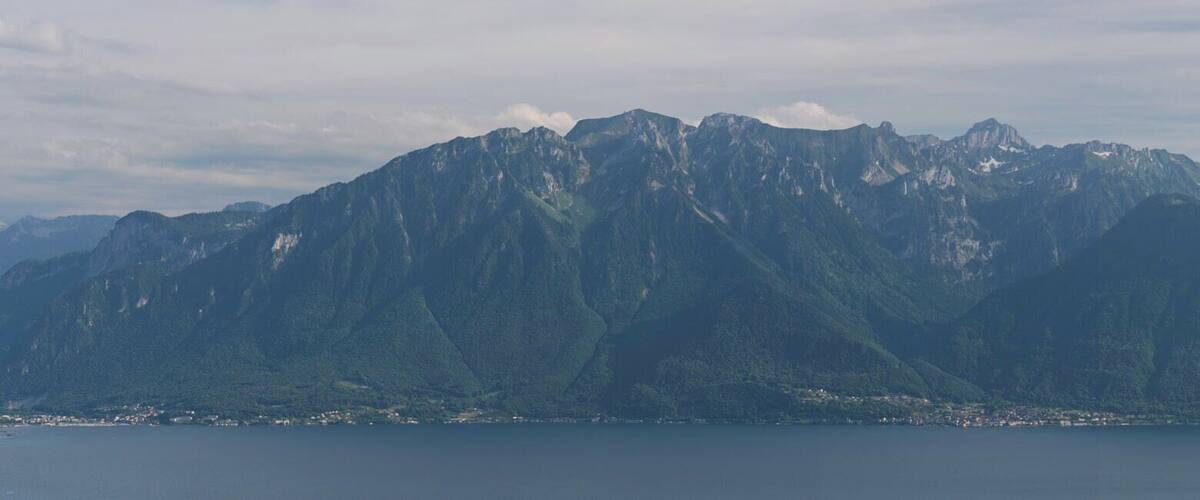 A mountain range with a lake in the foreground and a town at the base.