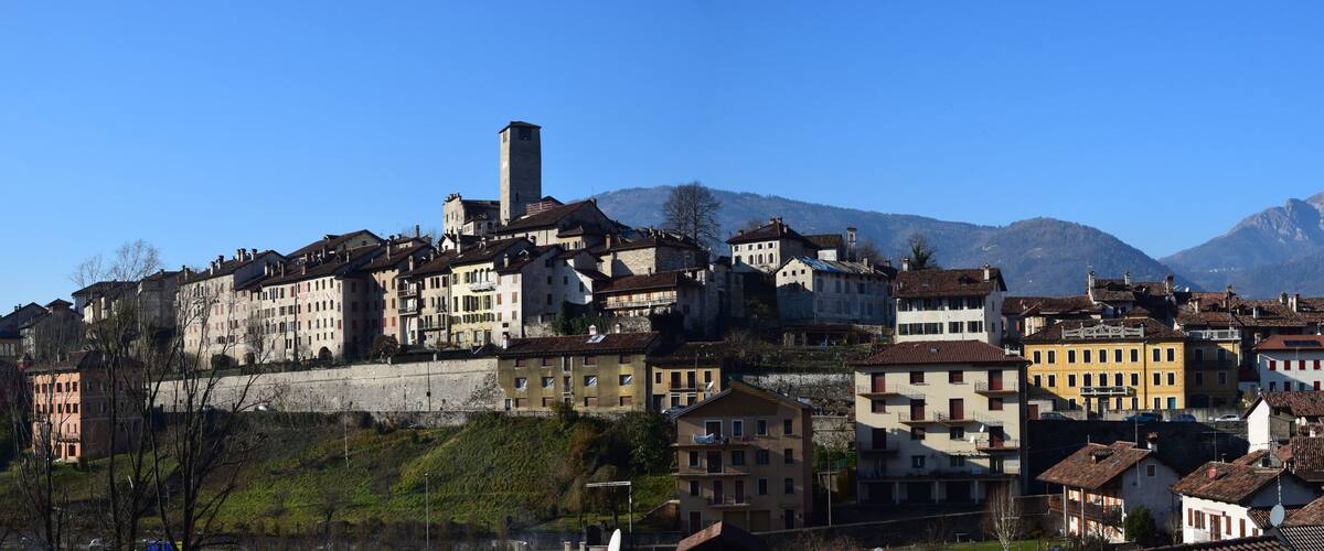 A historic town with a prominent tower, colorful buildings, and a backdrop of mountains.