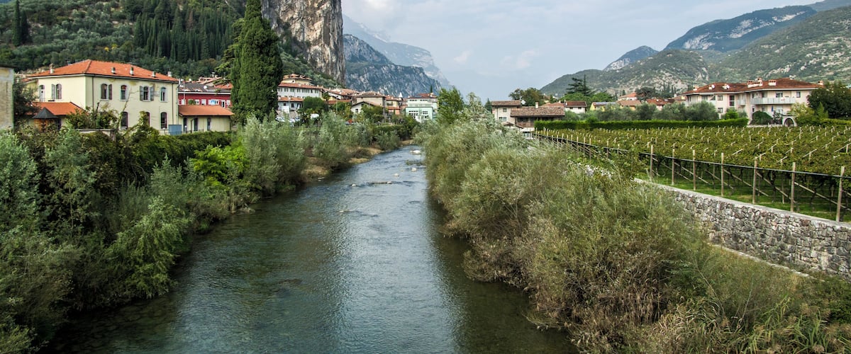 A river flowing through a town with buildings and a castle on a hill.