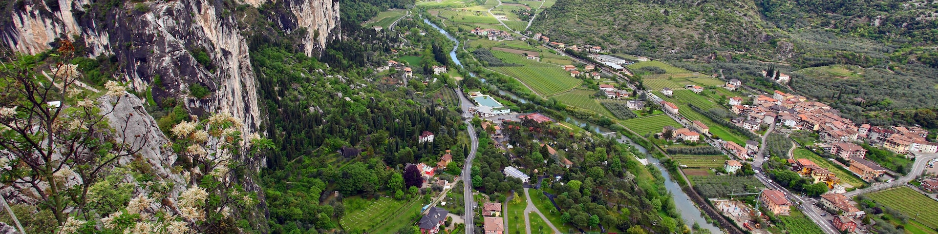 Paesaggio montuoso con un fiume, un piccolo paese e un edificio scolastico.