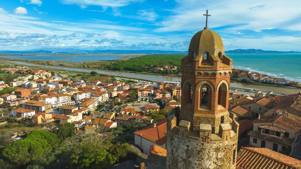 A coastal town with a prominent church tower, a river, and a beach.