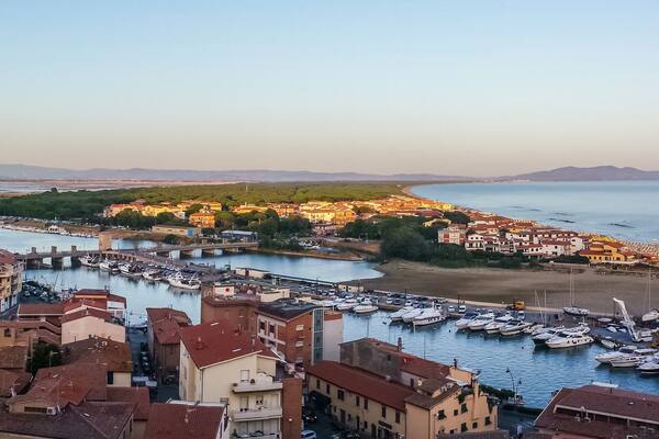 Una cittadina costiera con un porto turistico, edifici e un fiume.