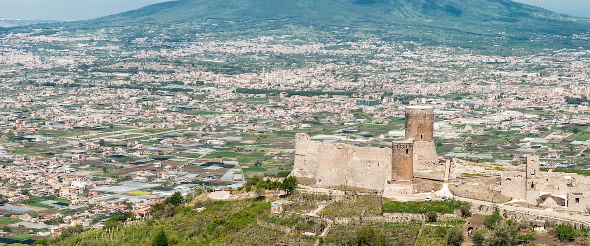 A cityscape with a prominent castle and a volcano in the background.