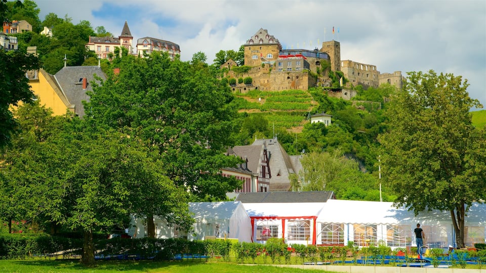 A castle on a hill with a hotel and a white tent in the foreground.