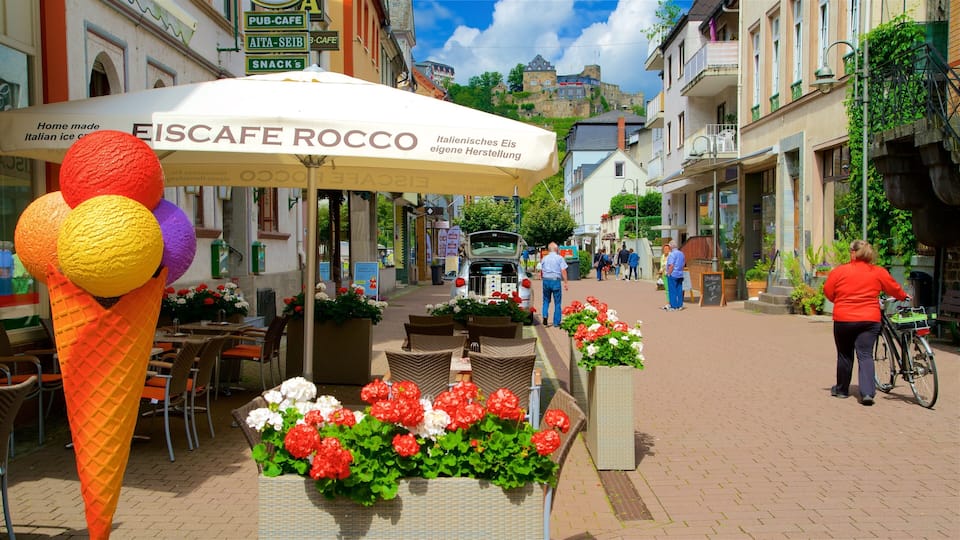 A street with a café named EISCAFÉ ROCCO, outdoor seating, and flower arrangements.